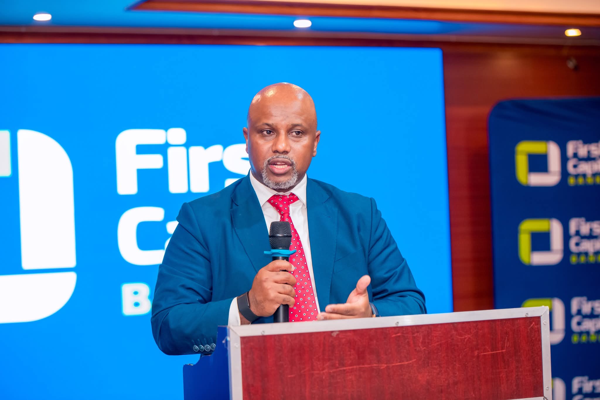 Lesego Osman speaking with a microphone at a branded podium.